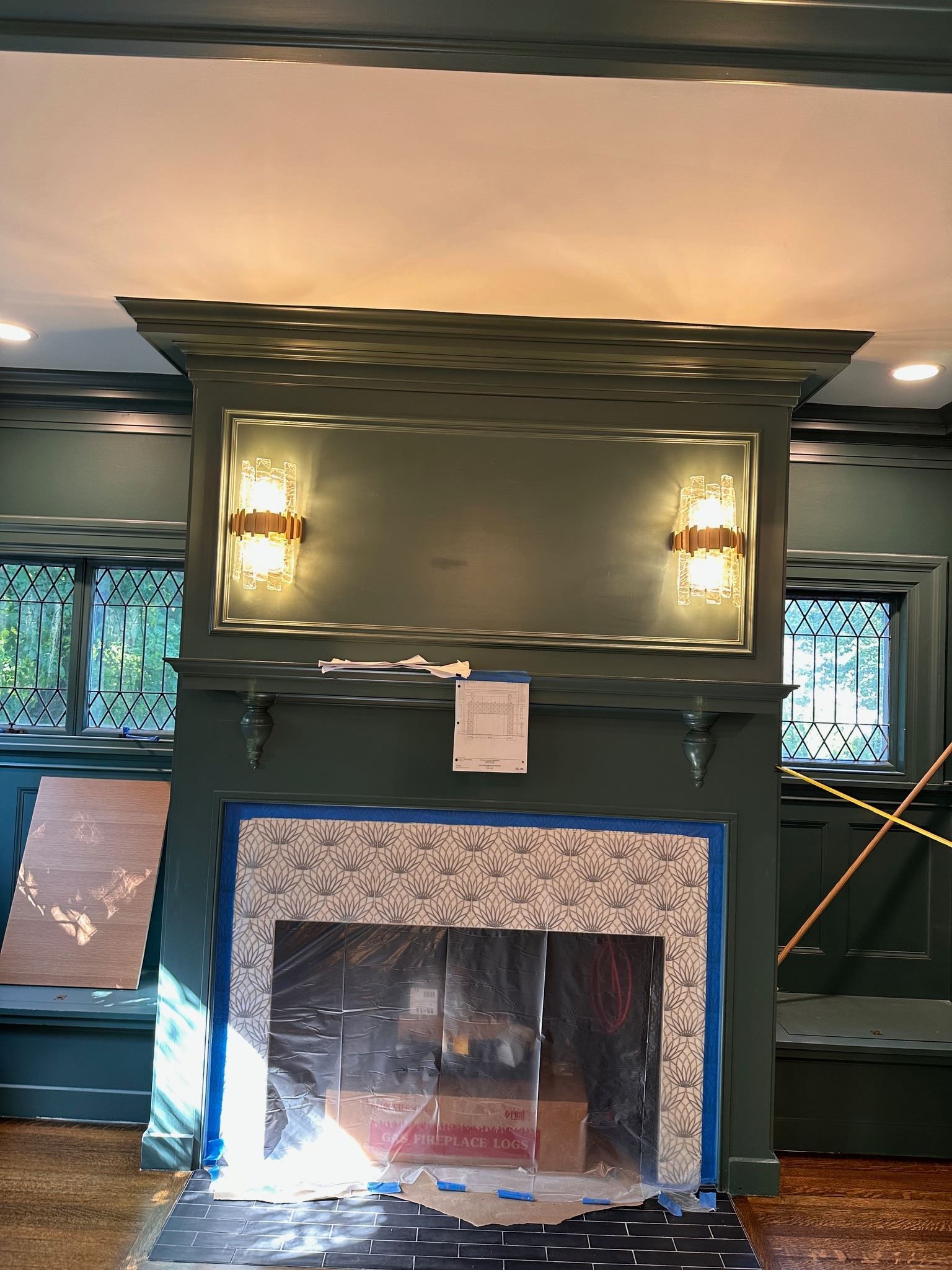 Living room fireplace with blue tile surround, dark mantel, wall sconces, and a mirror above the mantel
