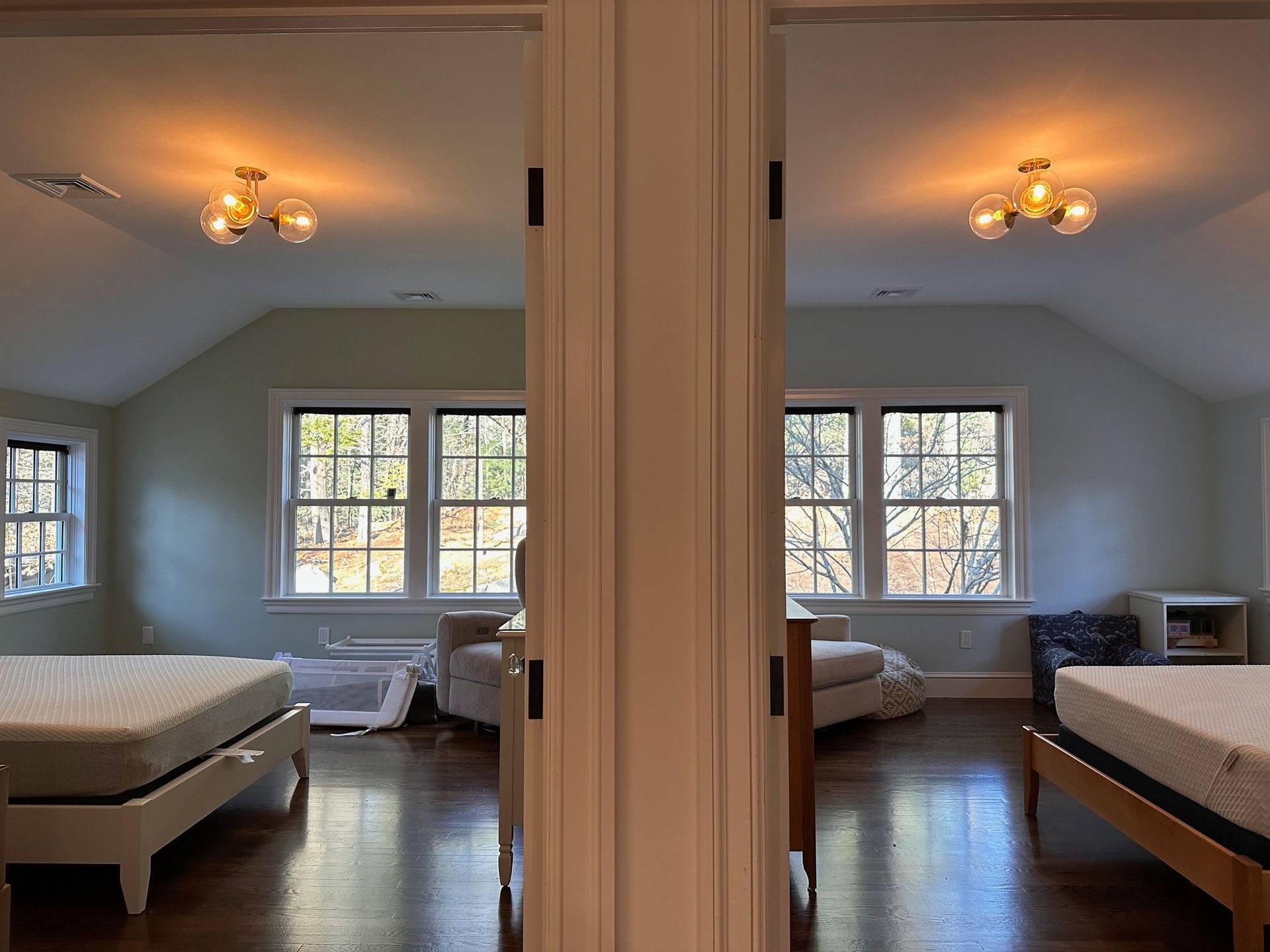 Two mirrored bedrooms with white beds, windows, and warm ceiling lights divided by a central wall.