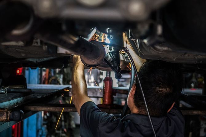 A man is working under a car in a garage.