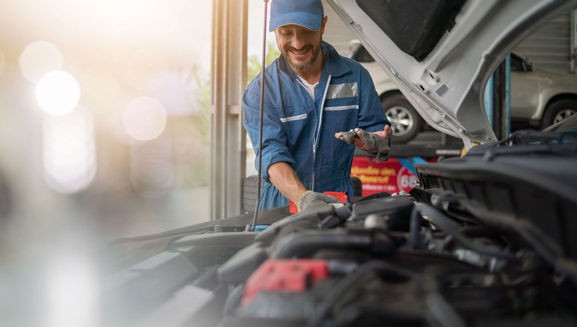A man is working on the engine of a car in a garage.