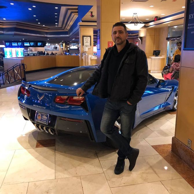 Reggie standing in front of a blue sports car