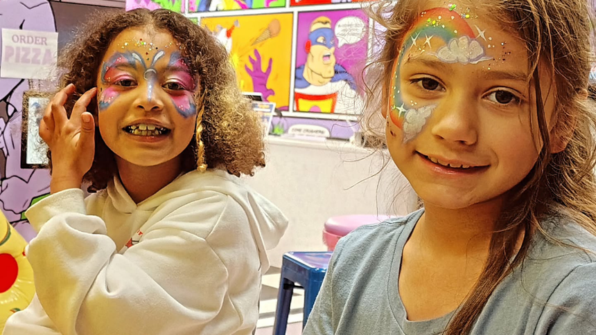 Two girls with face paint smile at the camera.