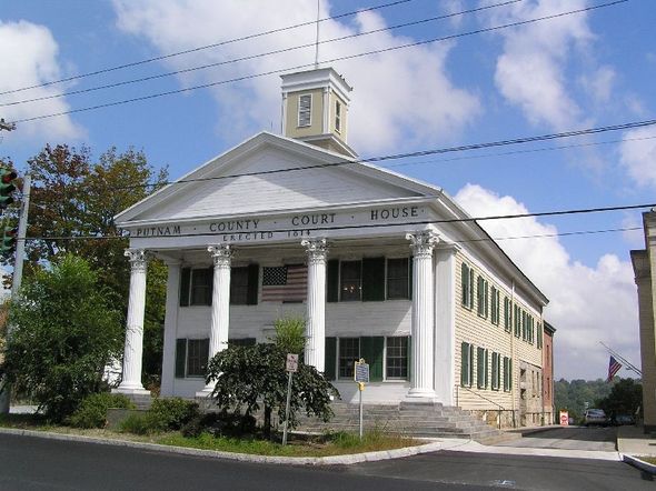 White church with columns and steeple on a street corner under a blue sky