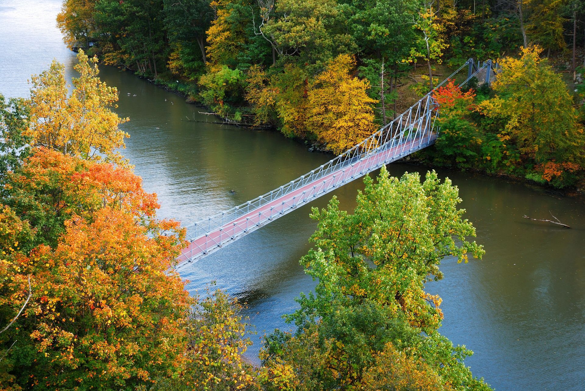 Footbridge crossing a river amid colorful autumn trees