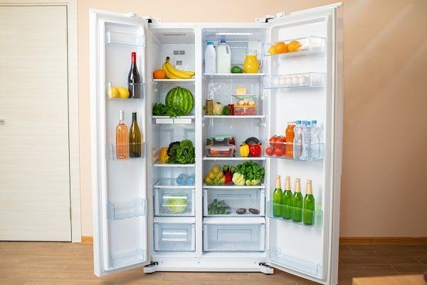 Un refrigerador abierto lleno de frutas y verduras en una sala de estar.