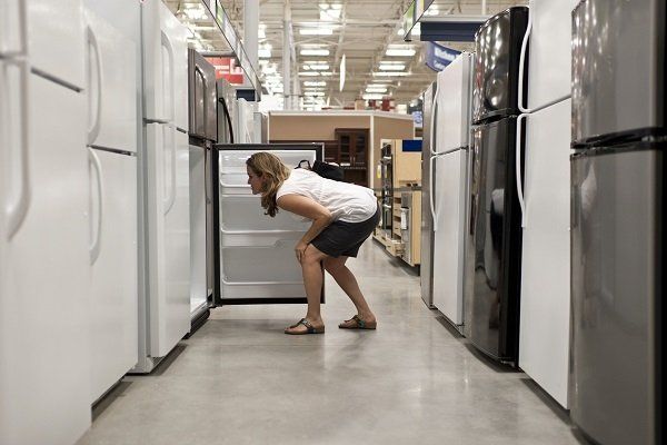 Una mujer está mirando un refrigerador en una tienda.