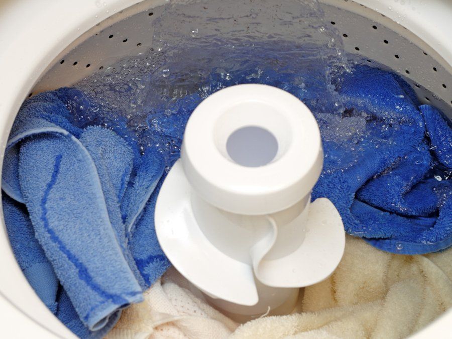 Una lavadora llena de ropa azul y blanca