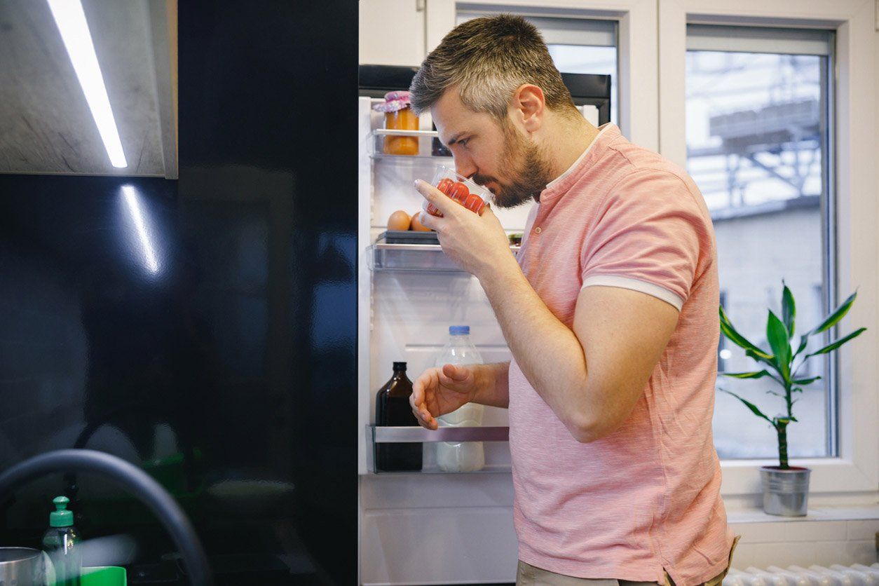 Un hombre está sacando algo de un refrigerador en la cocina.