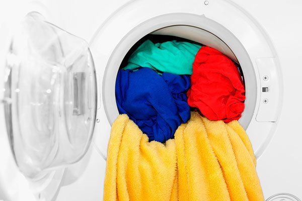 Una lavadora está llena de ropa de diferentes colores.