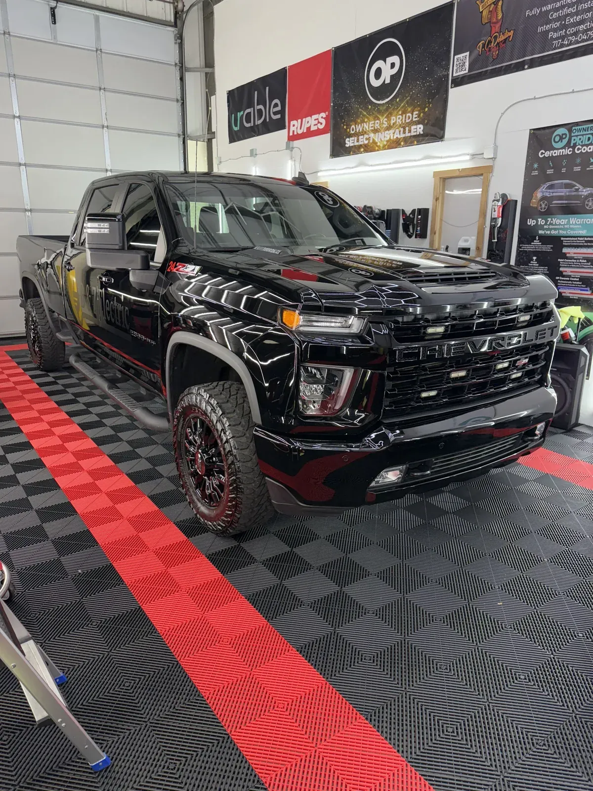 Black Chevrolet truck parked on red and gray checkered floor in a shop.