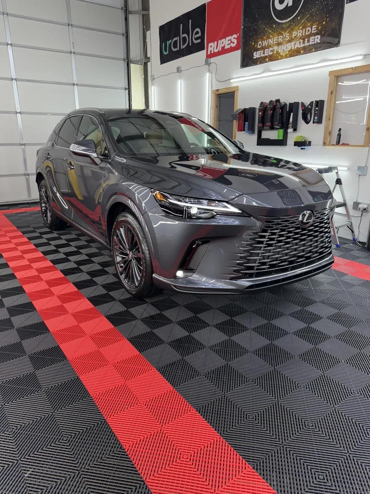 Dark gray Lexus RX SUV in a detailing shop on a red and black checkered floor.