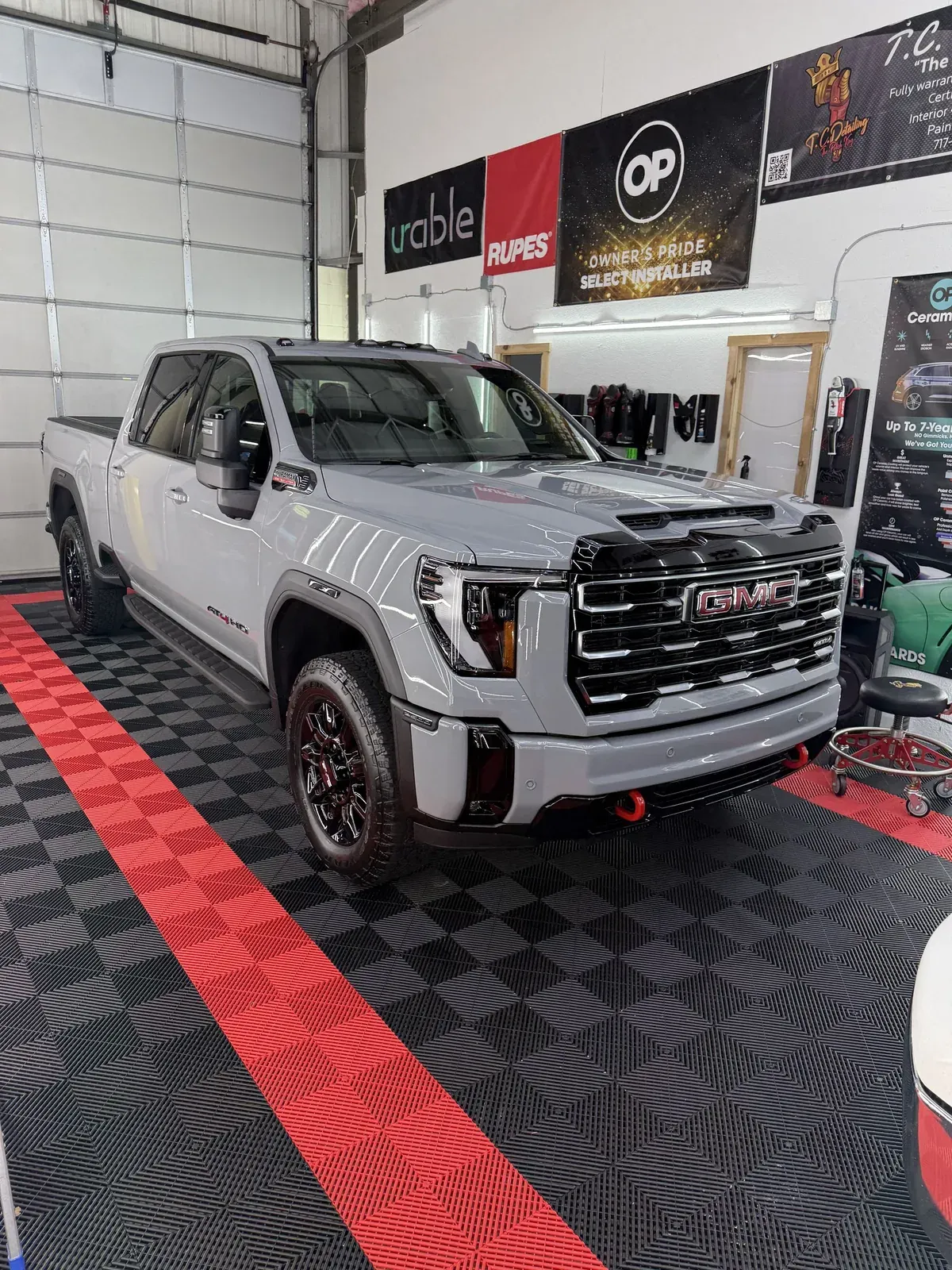 Gray GMC truck parked inside a garage on black and red floor tiles.