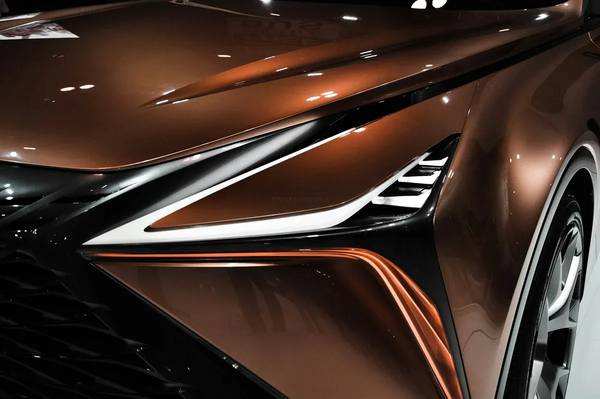 Close-up of a bronze-colored car's front with a sleek headlight design.
