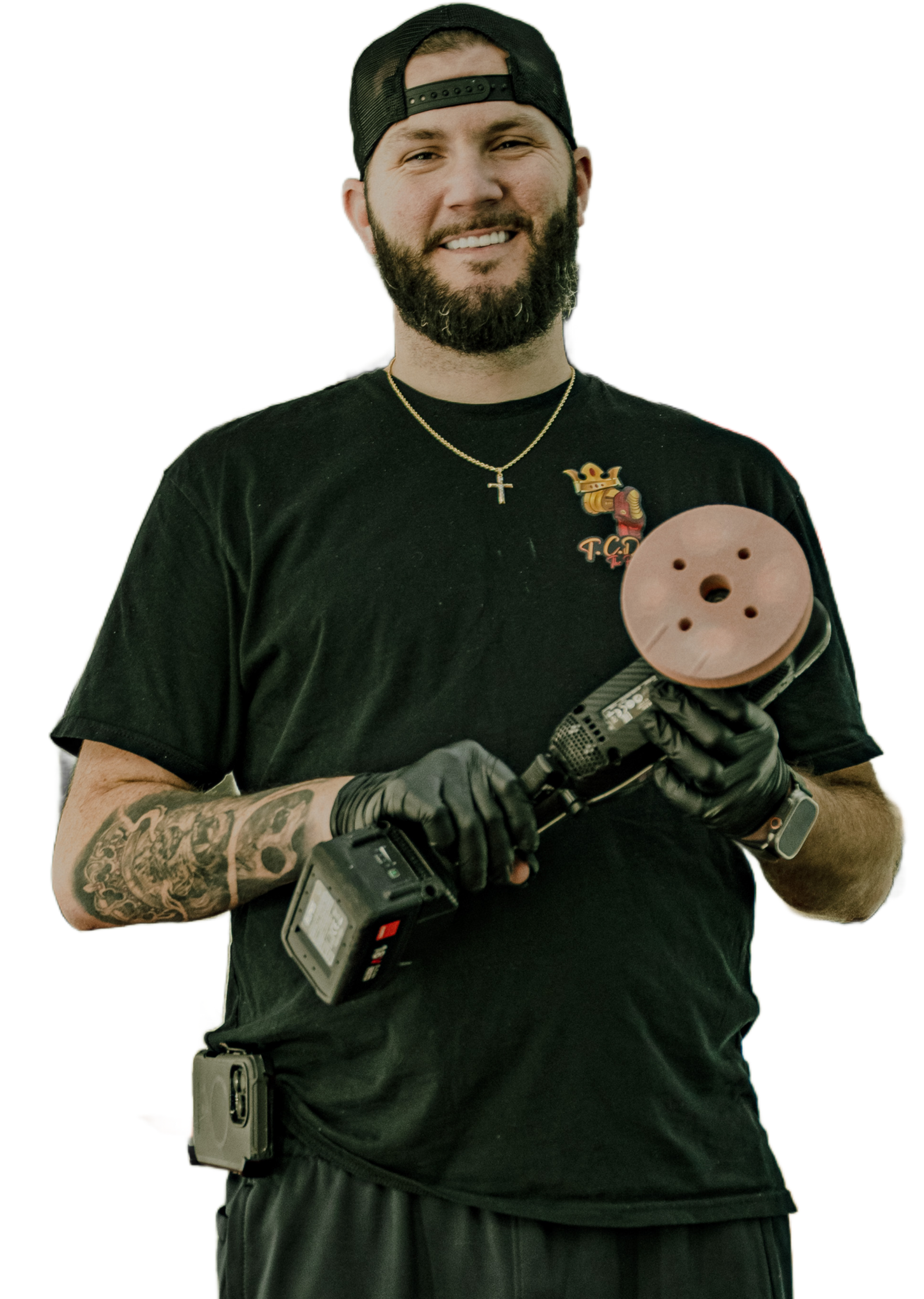 Man holding a polishing tool, wearing a black shirt, and a hat. He's smiling with a beard and gloves.