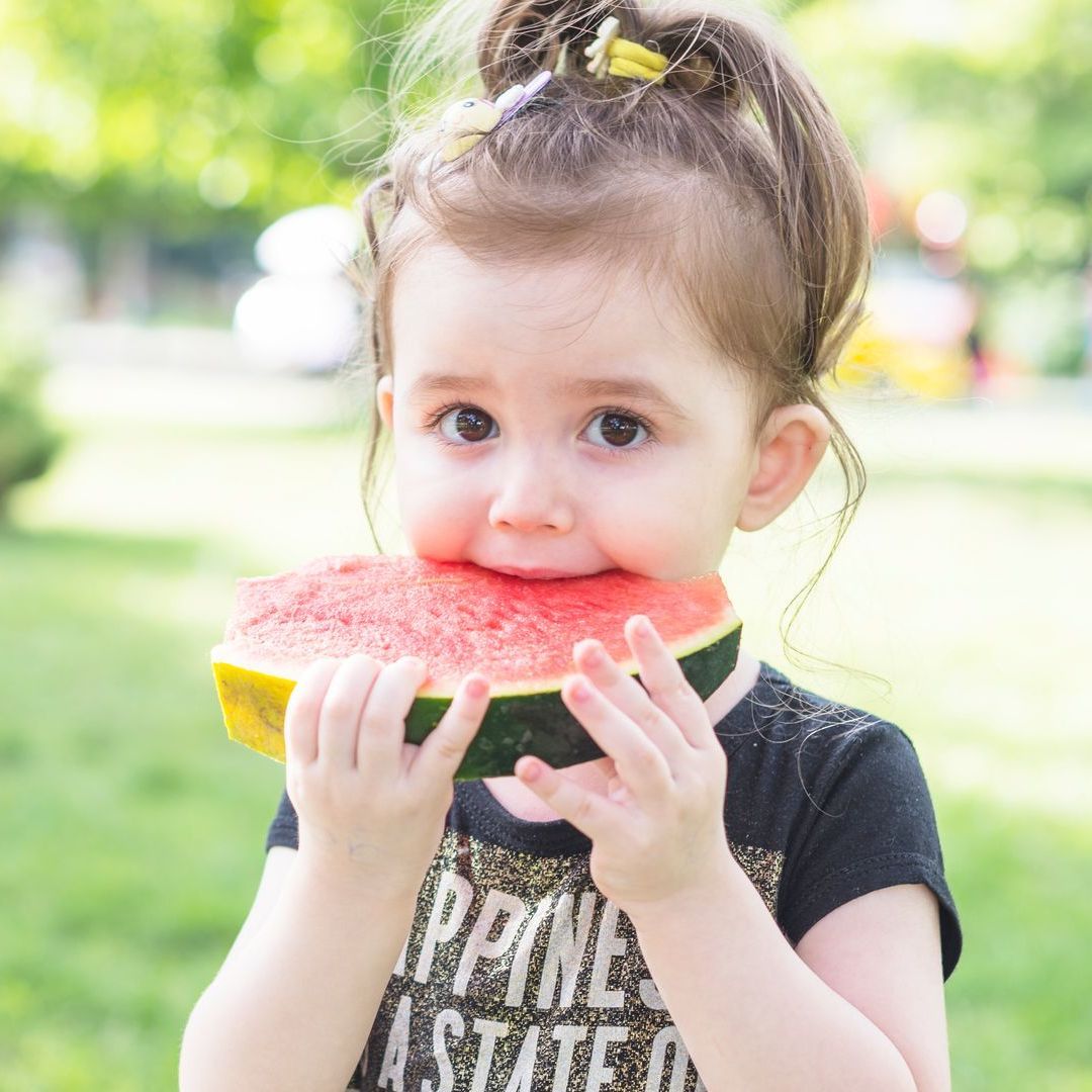 A little girl is eating a slice of watermelon