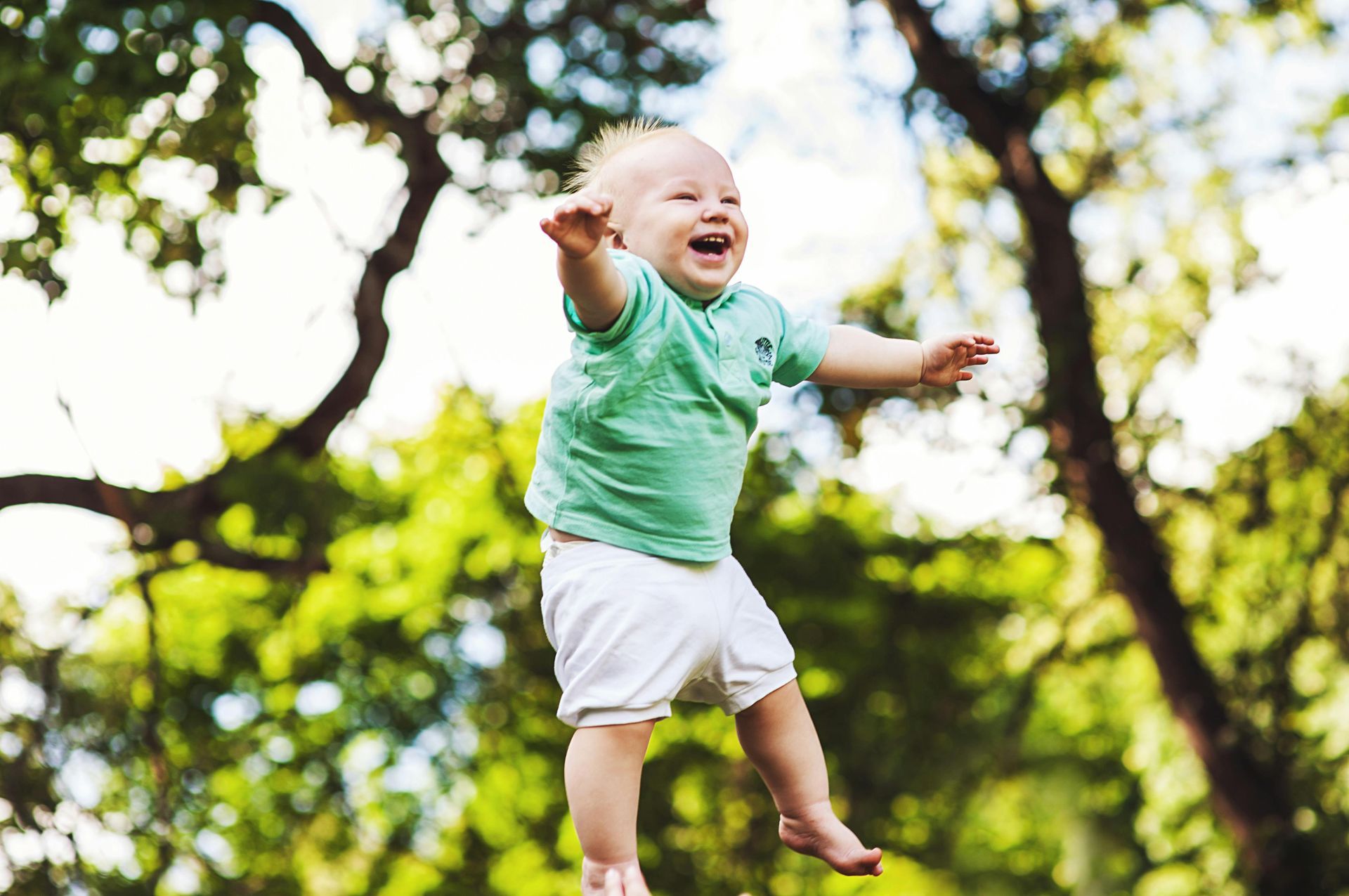 A baby is jumping in the air in a park.
