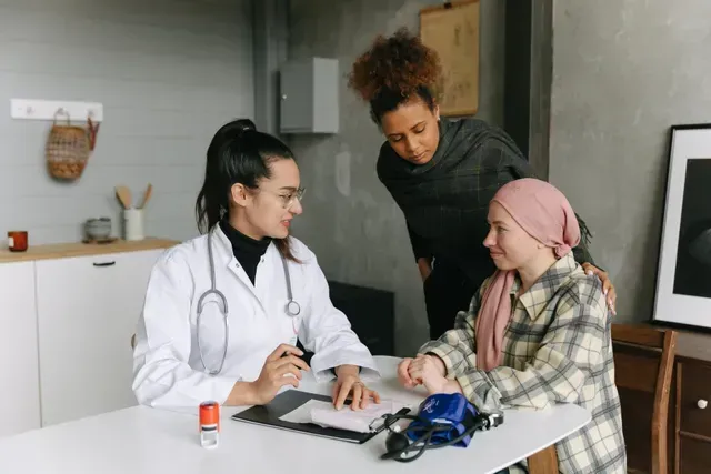 A doctor is talking to a child with cancer while a woman looks on.