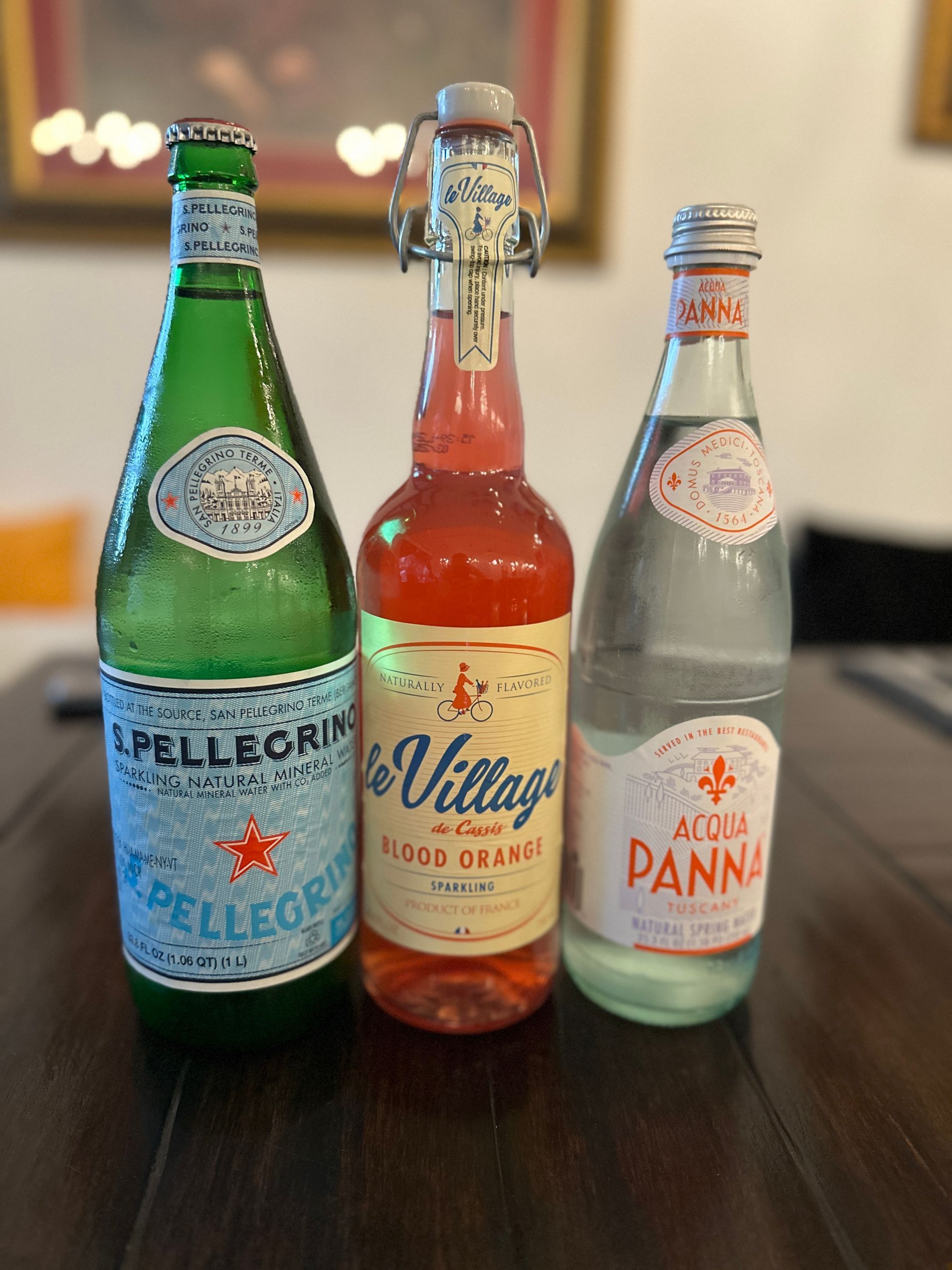 Three bottles of water are sitting on a wooden table
