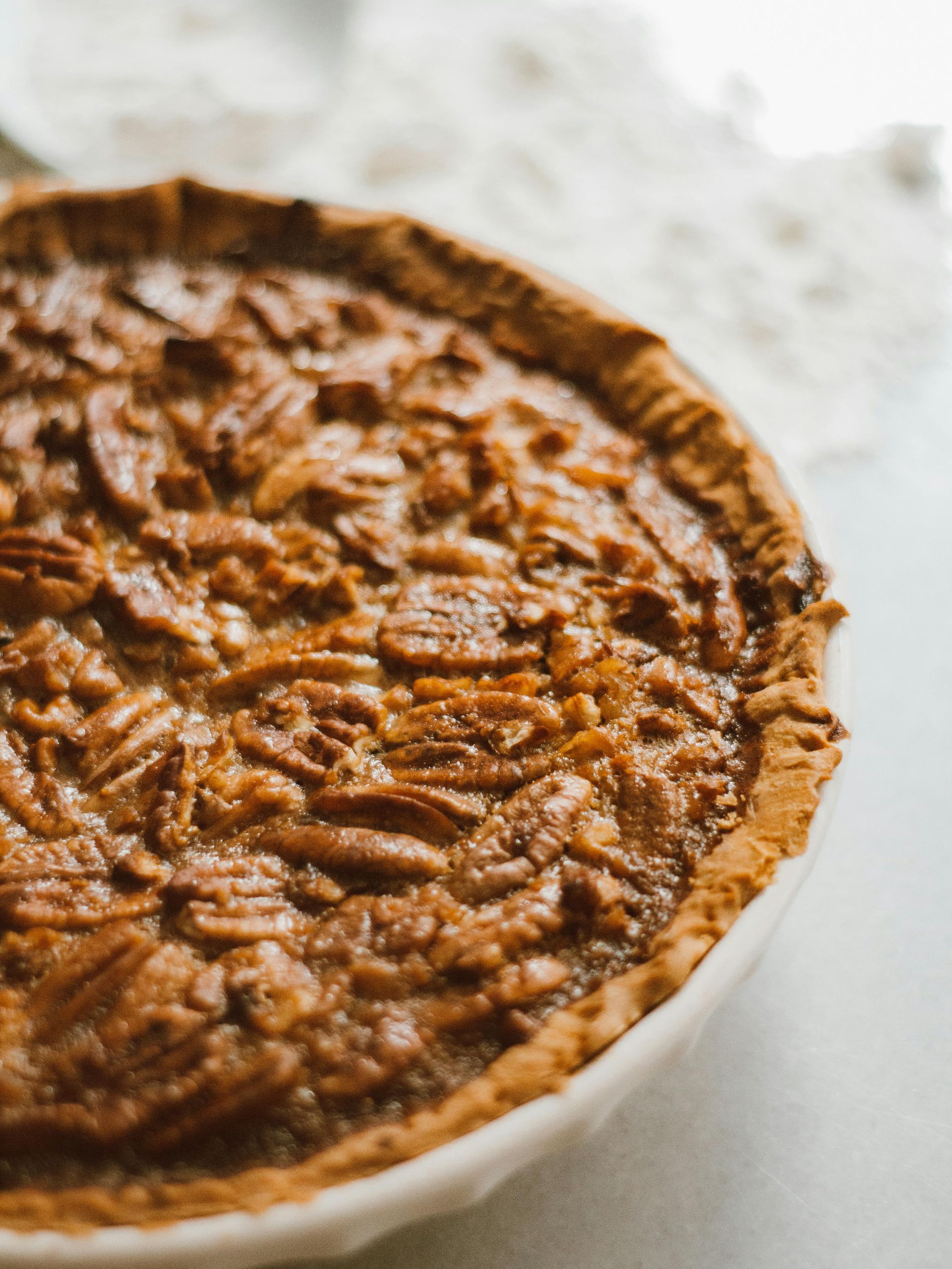 A pecan pie is sitting on a white plate on a table.