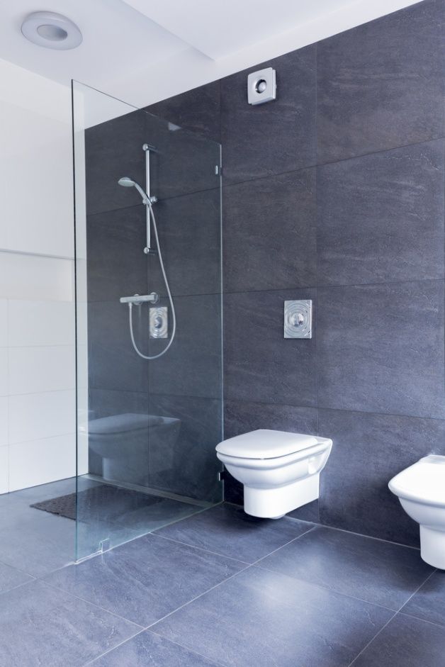 A bathroom with a walk in shower , sink , mirror and wooden walls.