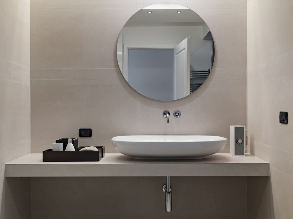 A Bathroom With A Sink And A Round Mirror — InStyle Shower Screens & Wardrobes in Wyong, NSW