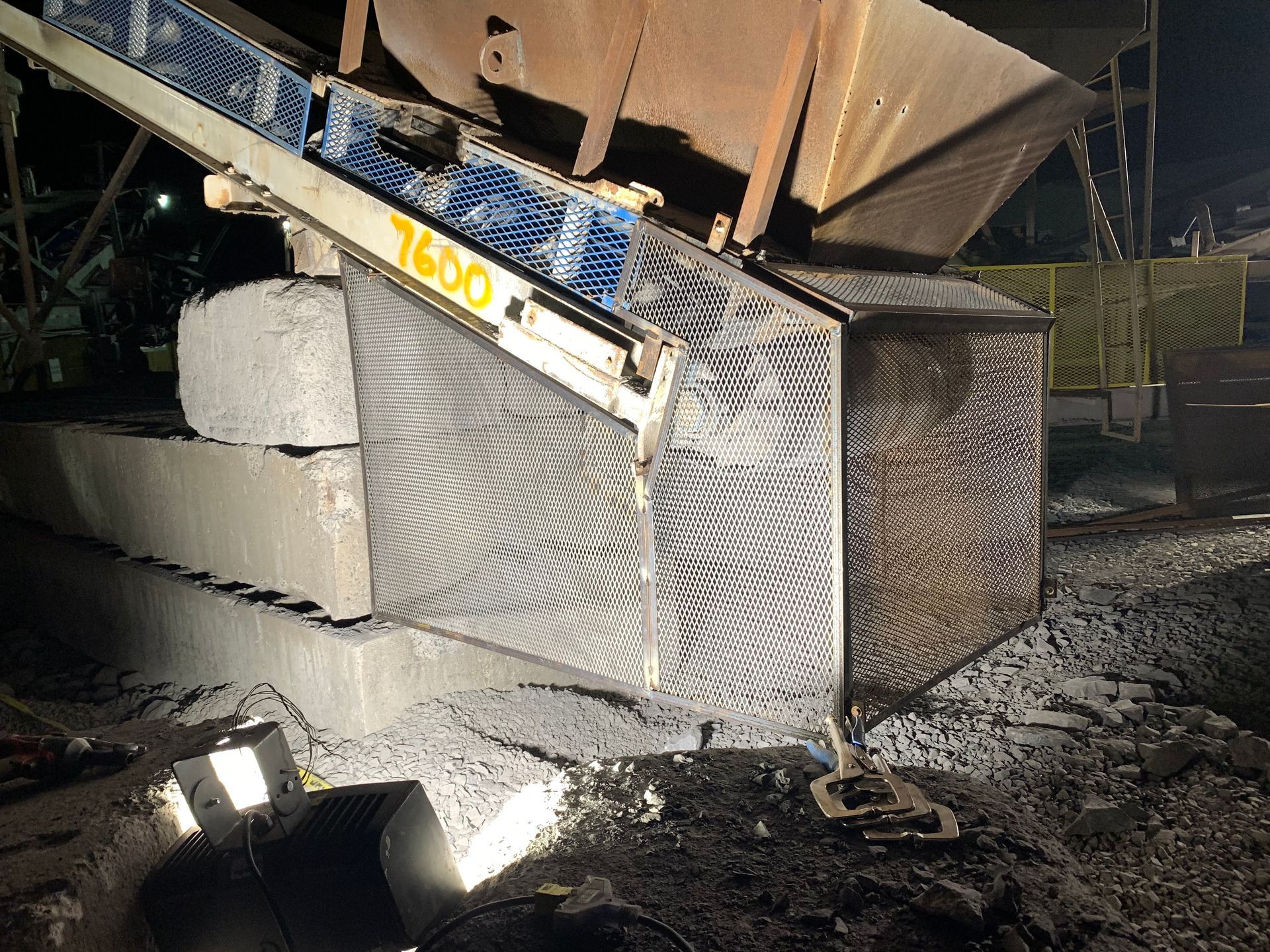 Tapis roulant déversant des matériaux sombres dans une benne, en milieu industriel.