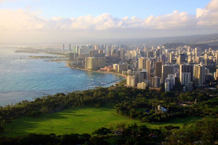 An aerial view of a city with a green field in the foreground An aerial view of a city with a green field in the foreground