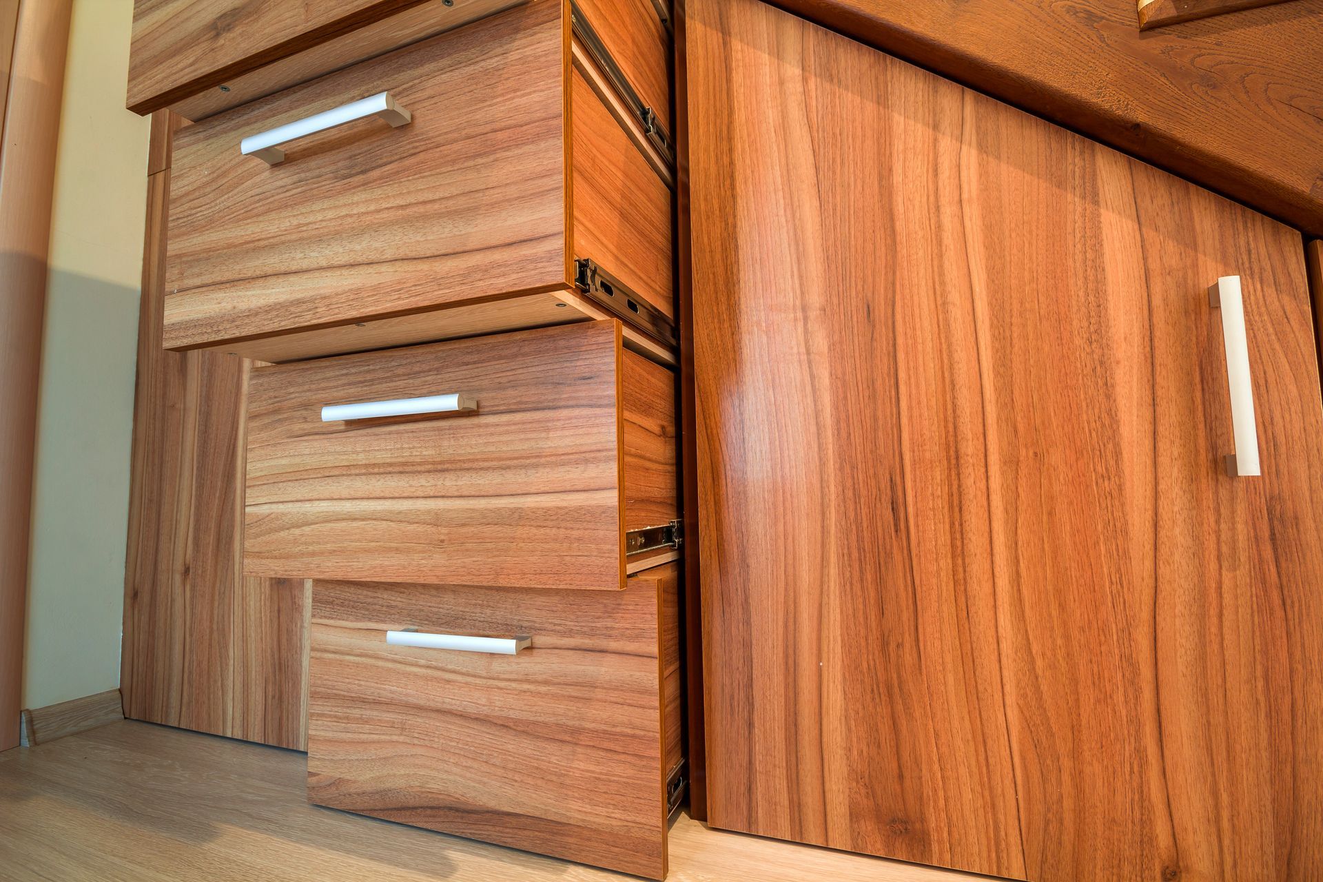 Wooden kitchen cabinets with three drawers and a cabinet door, viewed close-up from floor level. Wooden kitchen cabinets with three drawers and a cabinet door, viewed close-up from floor level.