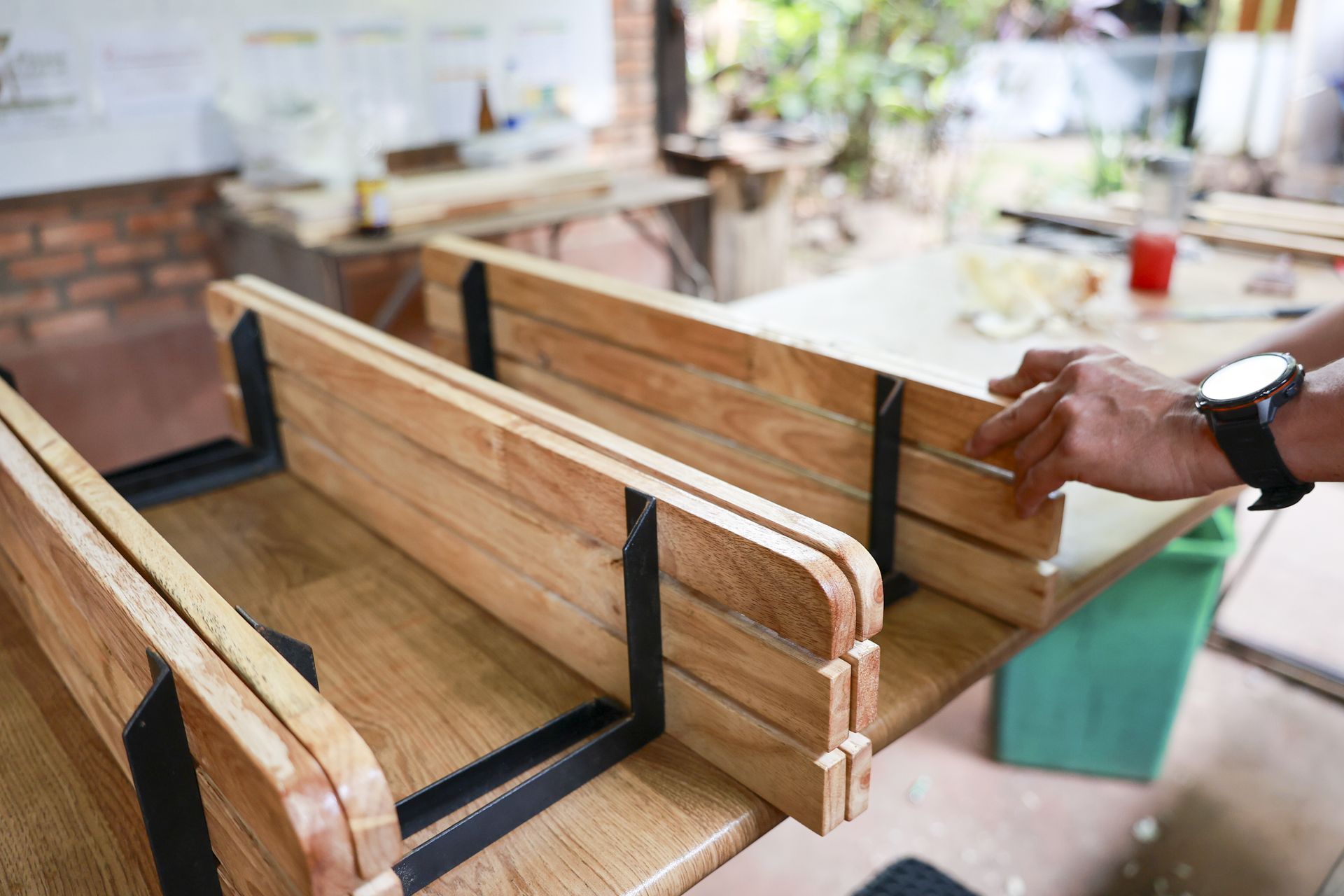 Wooden benches under construction in a workshop, with a hand adjusting one piece Wooden benches under construction in a workshop, with a hand adjusting one piece