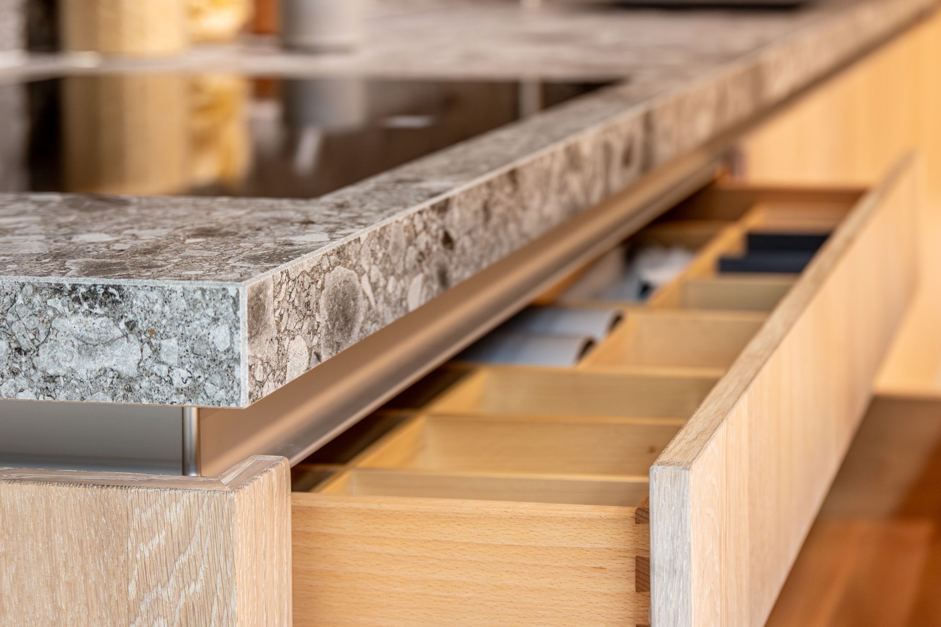 Granite kitchen countertop over an open wooden drawer with dividers