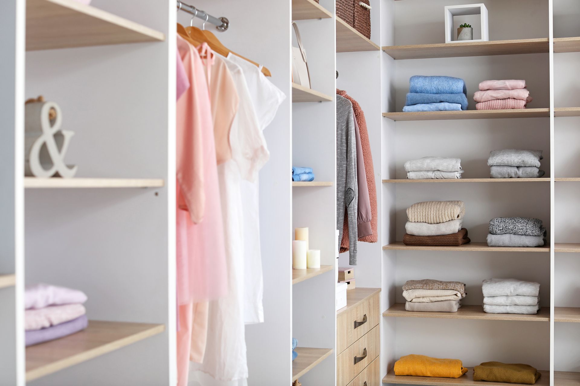 Open closet with hanging pastel clothes and neatly folded towels on shelves Open closet with hanging pastel clothes and neatly folded towels on shelves