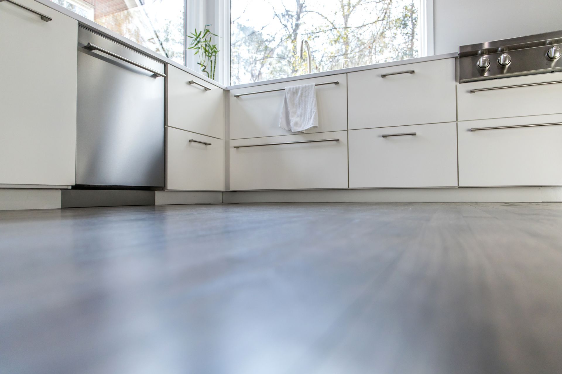 Modern white kitchen with stainless steel dishwasher and bright windows.