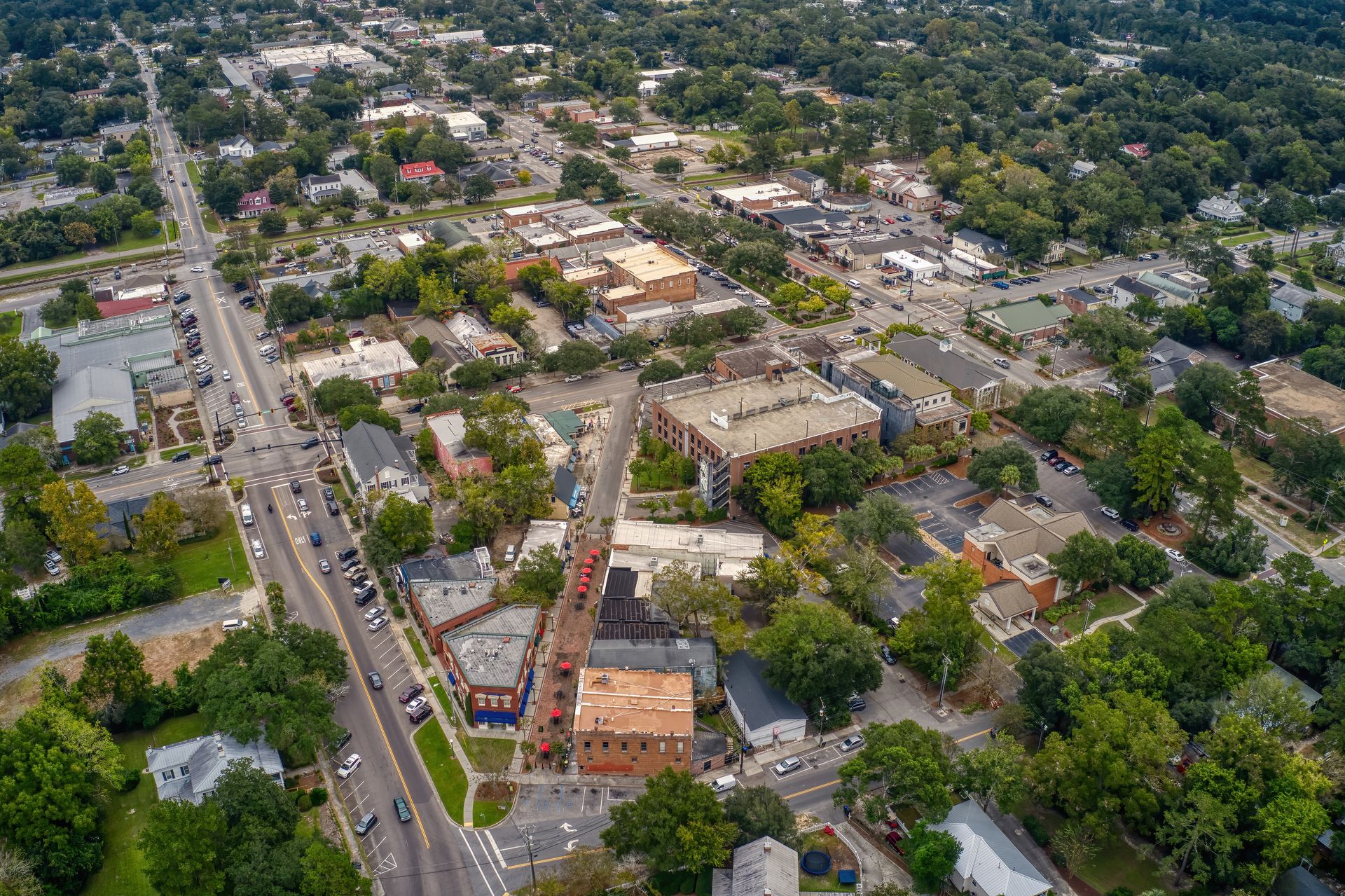 Aerial view of a suburban neighborhood with tree-lined streets, houses, and a busy road. Aerial view of a suburban neighborhood with tree-lined streets, houses, and a busy road.