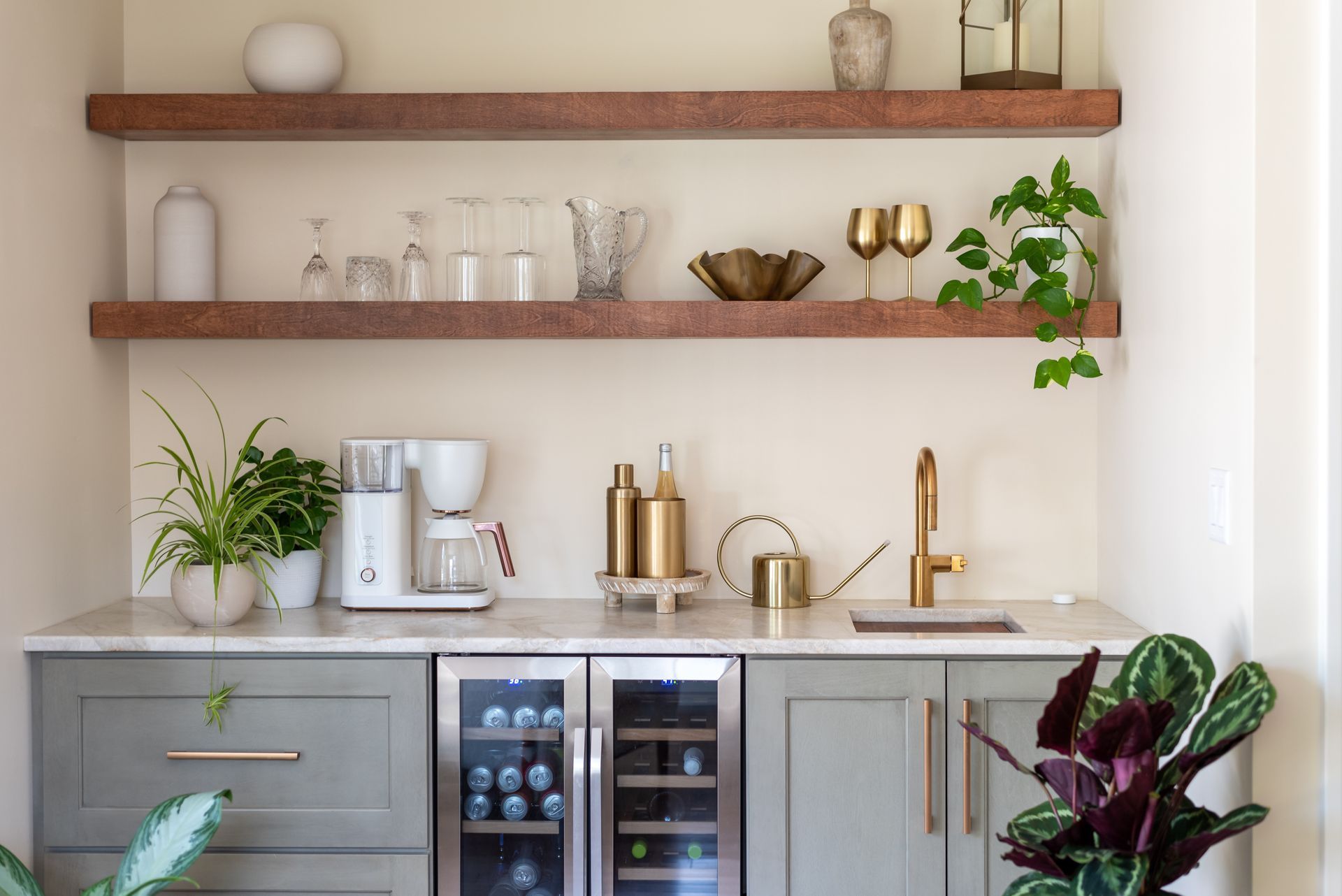 Modern kitchen coffee bar with wood shelves, espresso machine, gold accents, plants, and a wine fridge Modern kitchen coffee bar with wood shelves, espresso machine, gold accents, plants, and a wine fridge