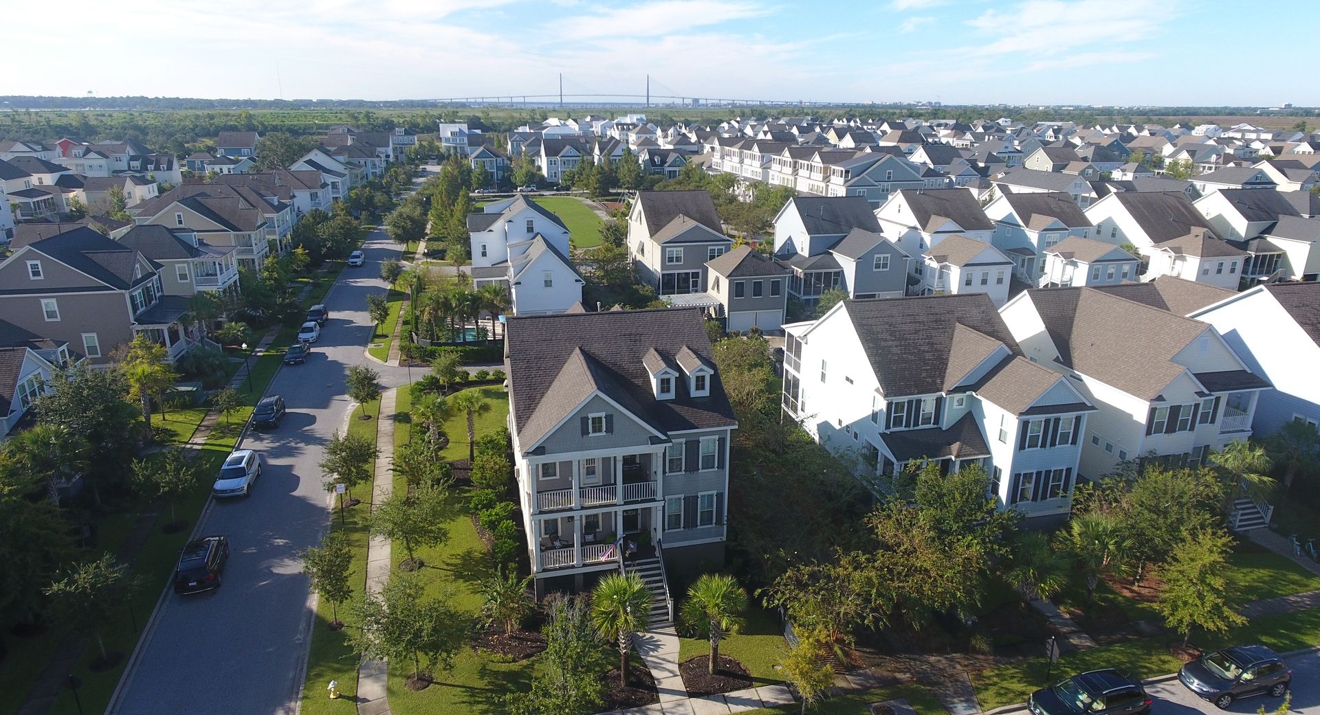 Aerial view of a suburban neighborhood with rows of houses and tree-lined streets under clear skies Aerial view of a suburban neighborhood with rows of houses and tree-lined streets under clear skies
