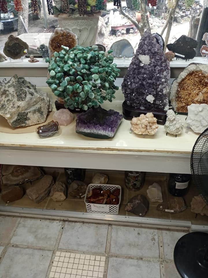 Display of colorful crystal and mineral specimens on white shelves in a shop
