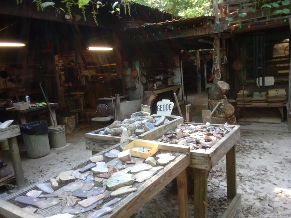 Outdoor workshop with tables covered in stone fragments and tools in a rustic courtyard