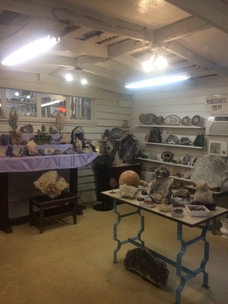 Rock and mineral display room with shelves, tables, and fluorescent lights in a basement-like space
