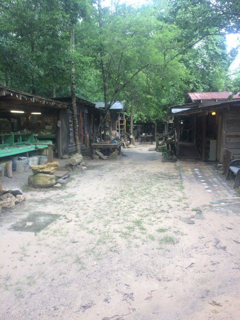 Wooded outdoor market path with rustic stalls and green trees on both sides