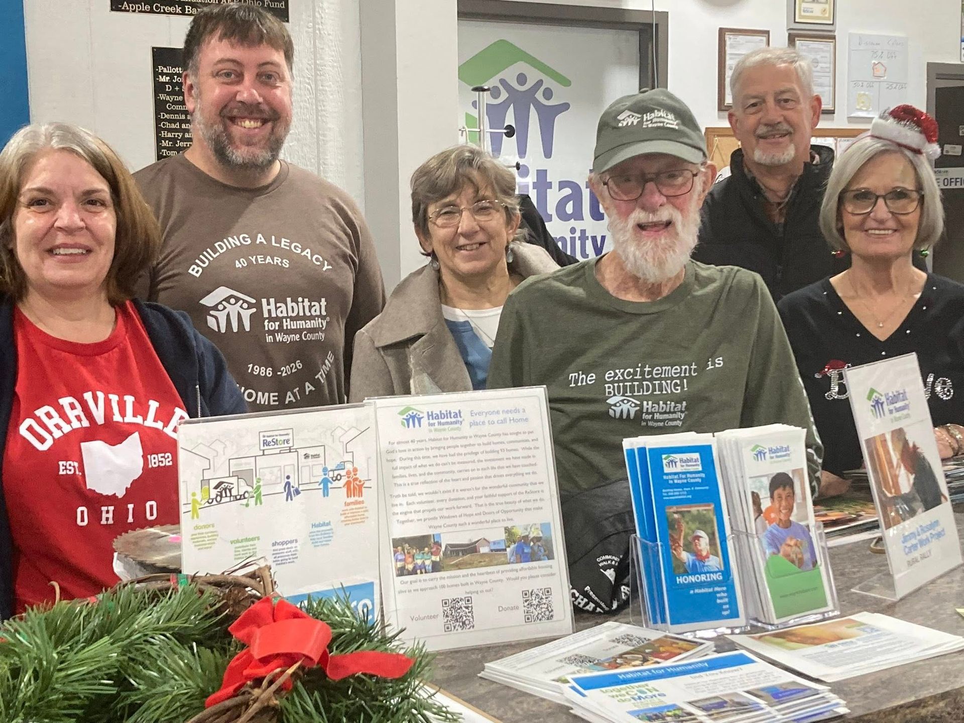 Group of volunteers smiling behind a table of brochures and donation items at a Habitat for Humanity event