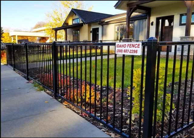 High Quality Materials A black fence with a sign on it is in front of a house.