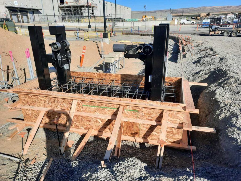 A large wooden box is sitting in the dirt on a construction site.