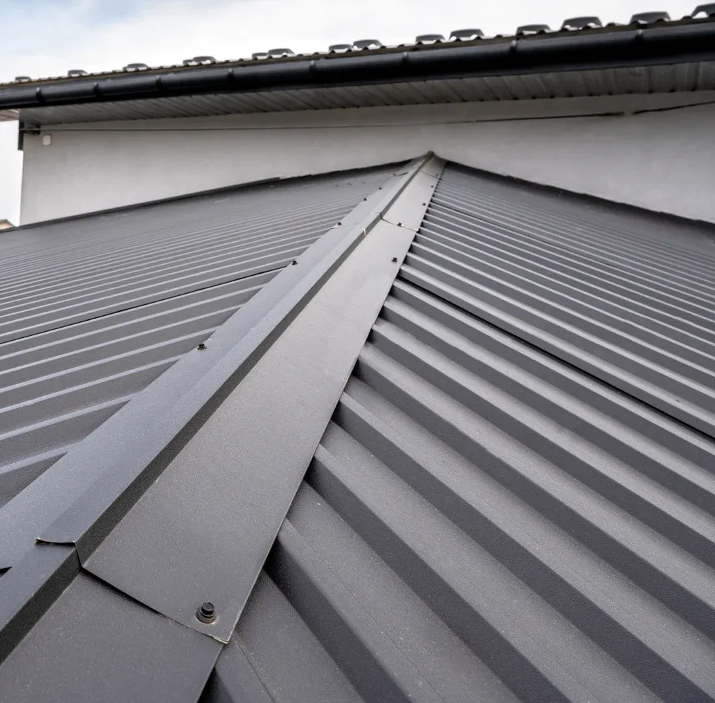 Gray metal roof with ridges and a central seam, near a building's upper edge.