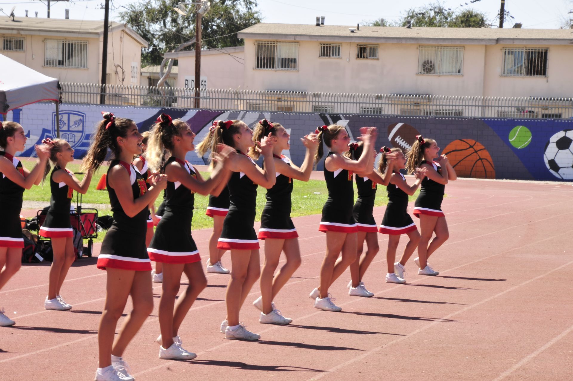 Cheer squad in black and red uniforms performing on an outdoor sports court
