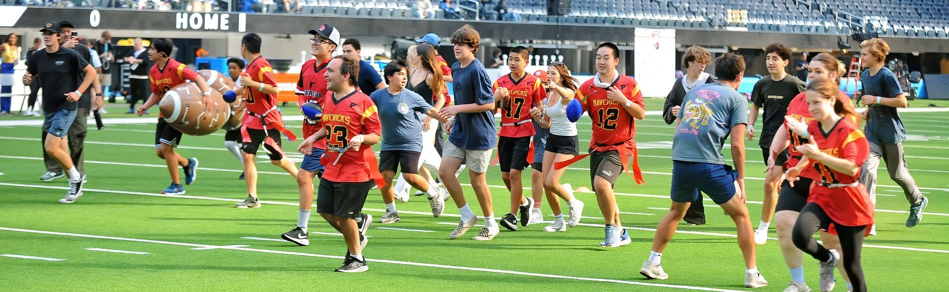 Athletes in colorful jerseys sprint during a rugby match on a green field.