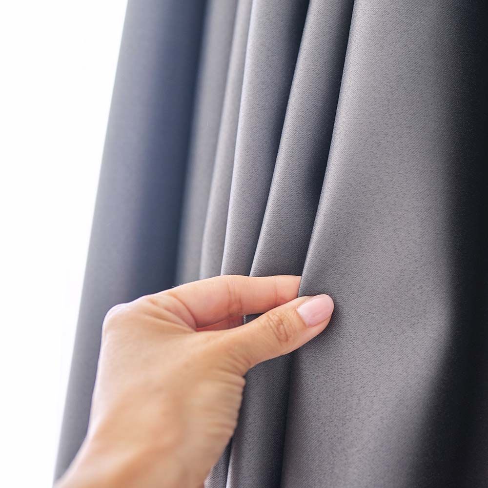 Hand holding up gray curtain.