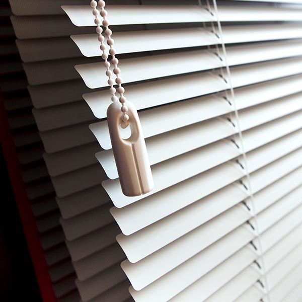 White horizontal blinds, partly open, with a pull chain hanging down.