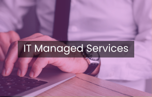 A man is typing on a laptop with the words it managed services above him