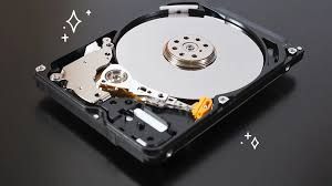 The inside of a hard drive is shown on a black surface.