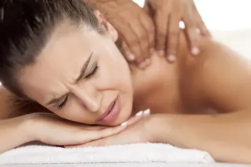 A woman is laying on a table getting a massage.